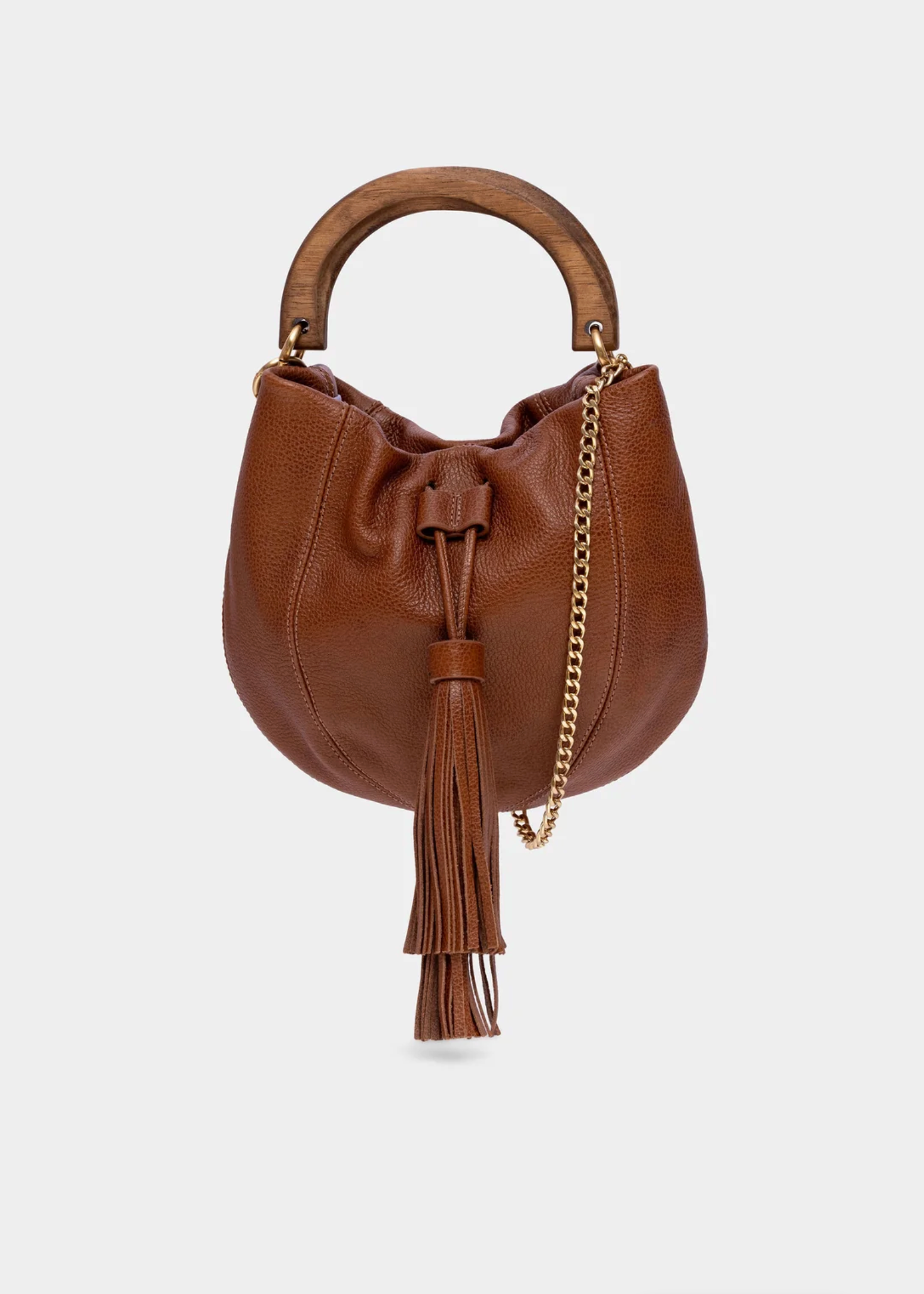 A brown pebbled leather crescent-shaped bucket bag with a wooden top handle, a gold chain strap, and a matching leather tassel, shown against a light gray background.