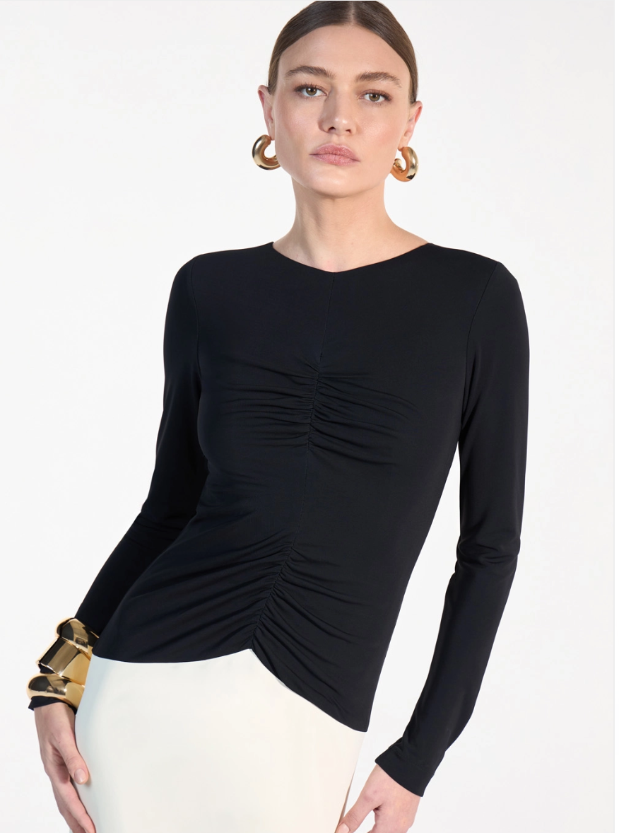 Woman wearing a black long-sleeve top with ruched design on a white background