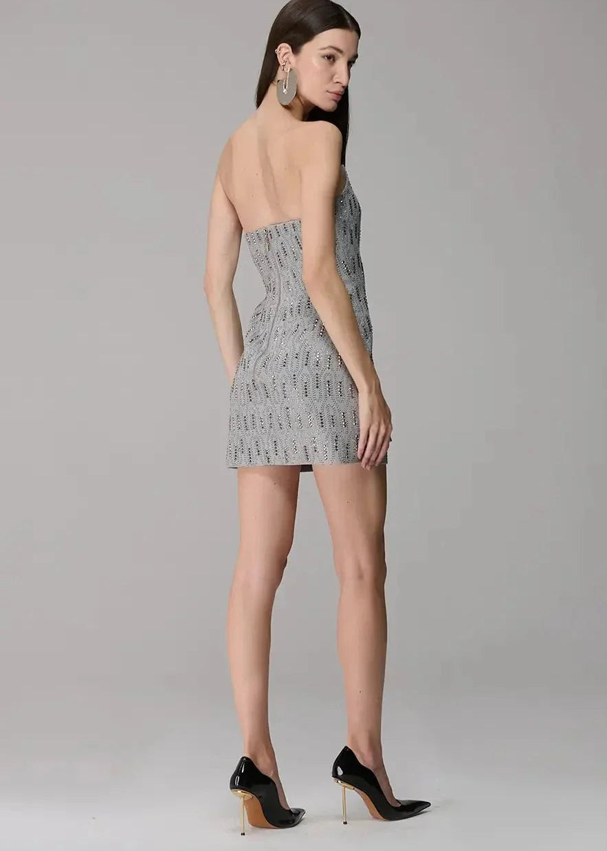 Woman wearing a strapless patterned dress on a plain background