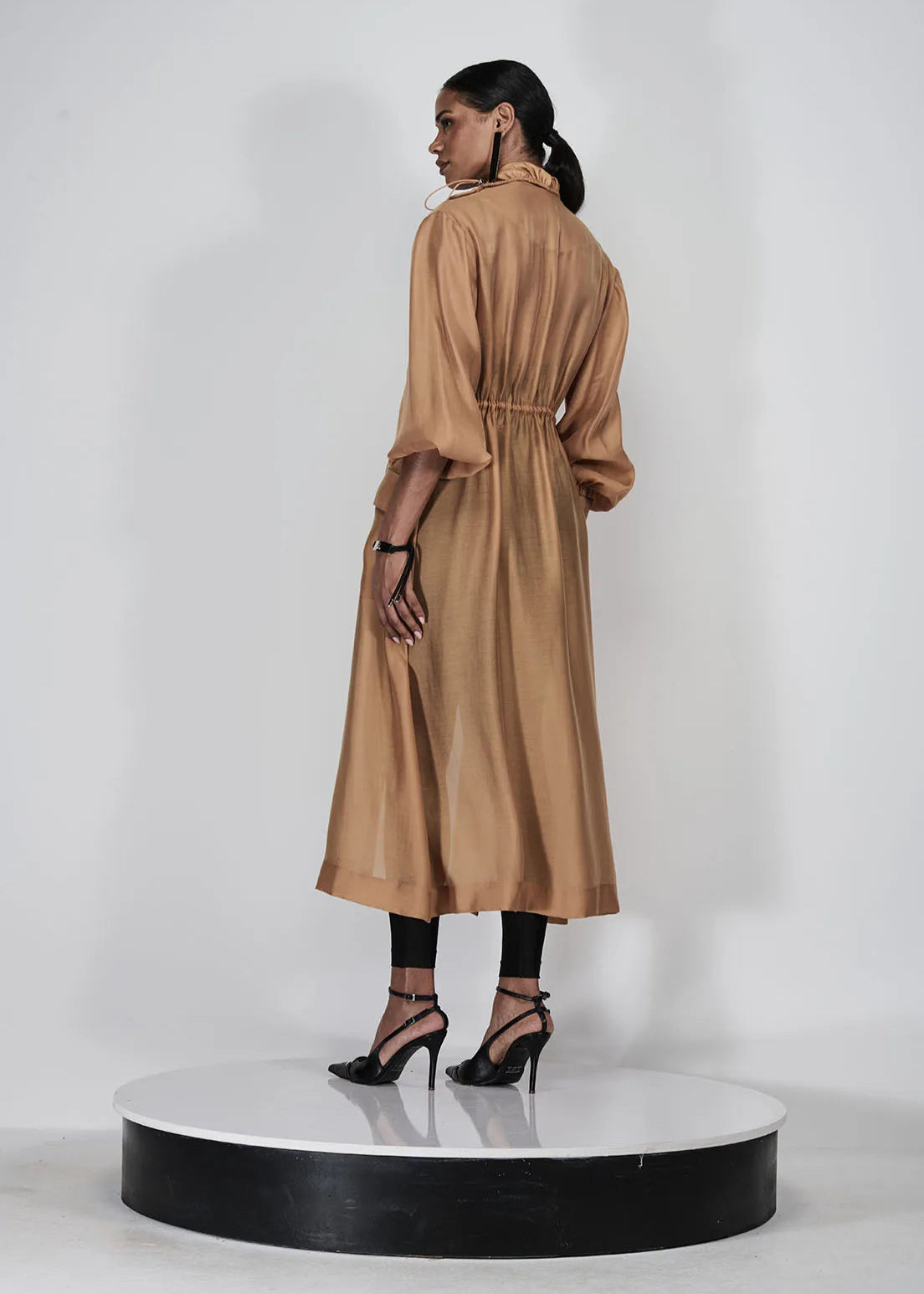 Woman wearing a long beige dress on a white background