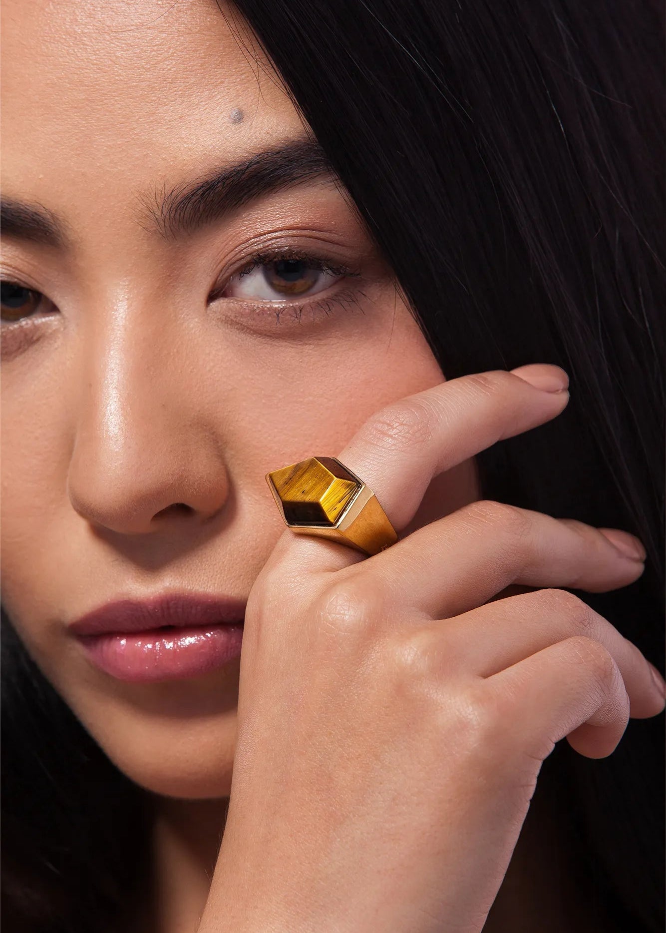 Close-up of a woman wearing a gold ring with a large gemstone.