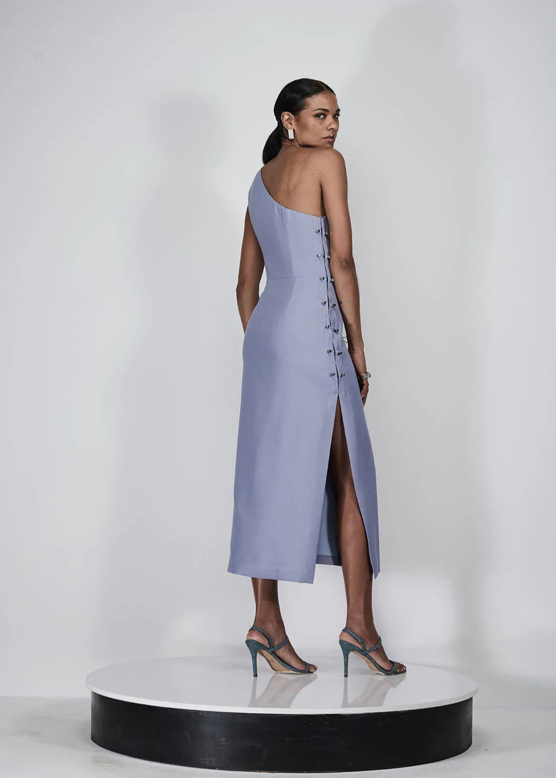 Woman wearing a one-shoulder dress with a slit on a white background