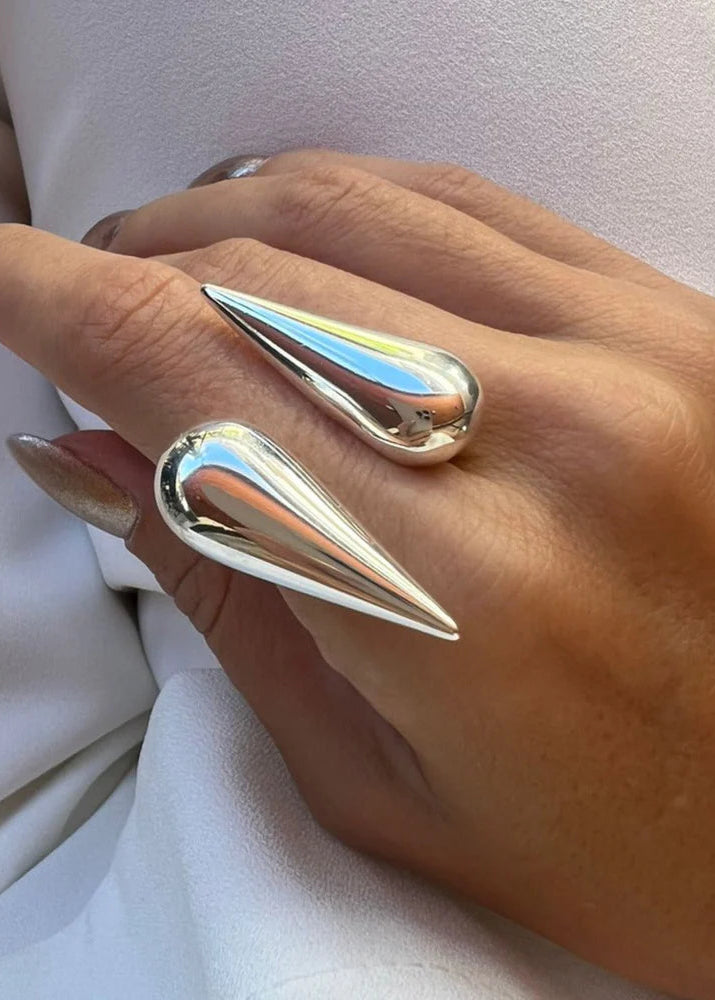 Hand wearing two metallic spike rings on a white background
