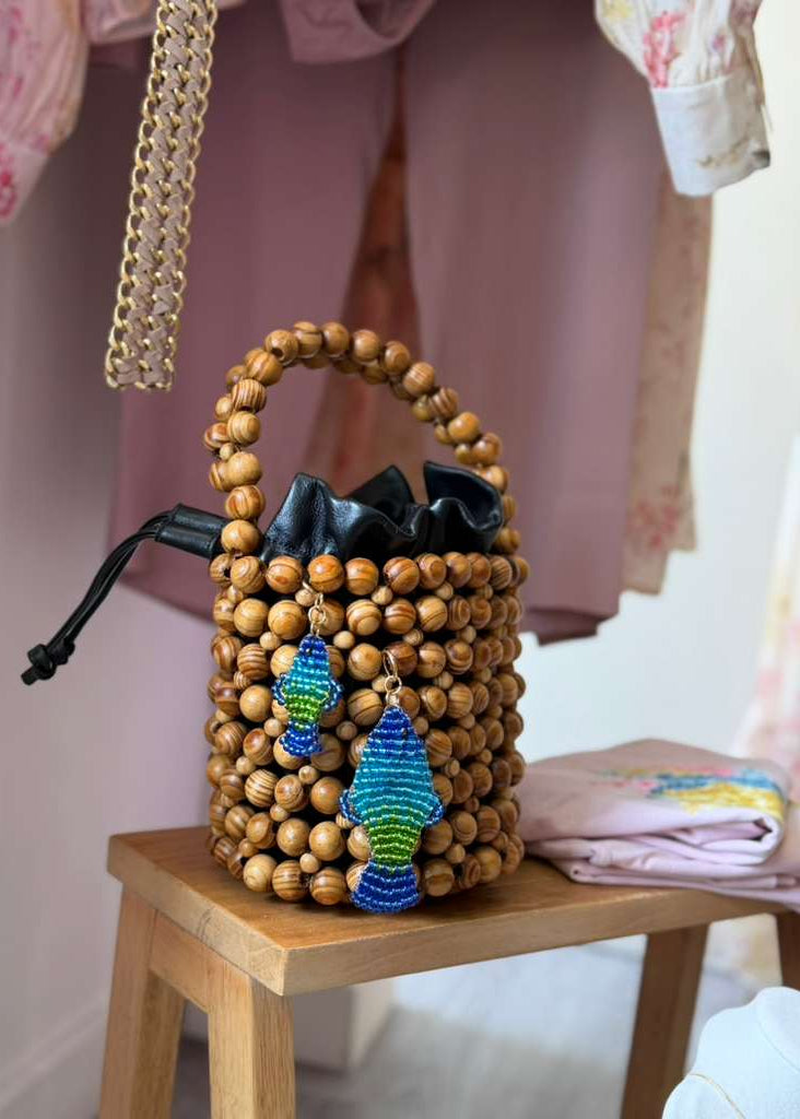 Wooden beaded handbag with colorful accents on a wooden stool