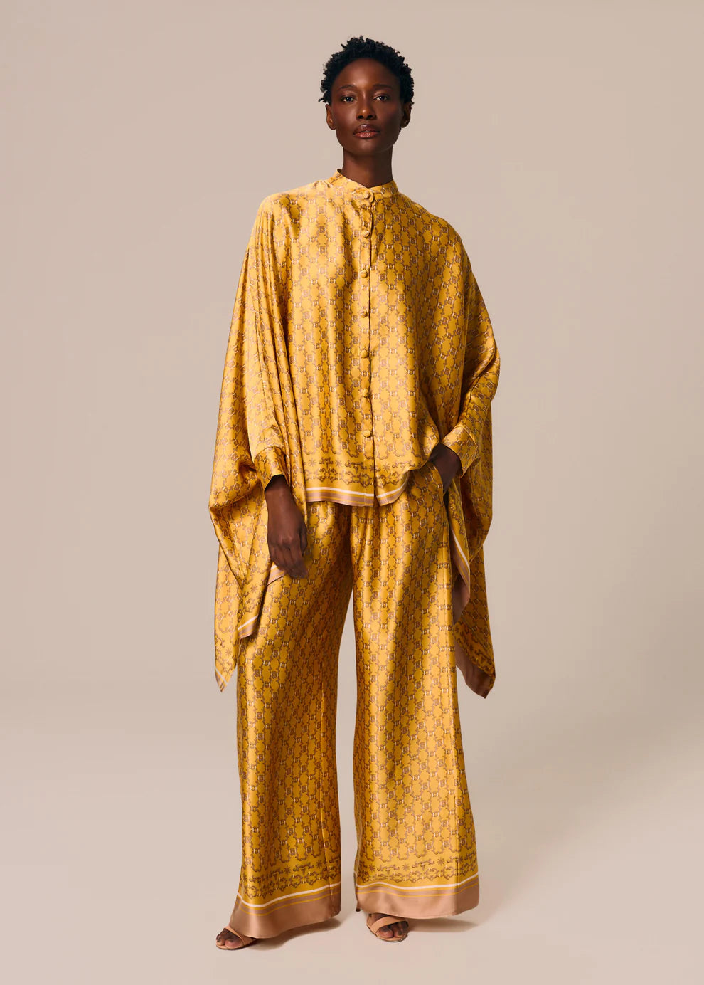 Person wearing a mustard yellow patterned outfit on a beige background