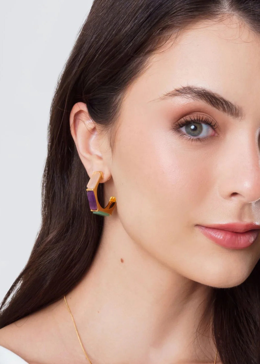 Close-up of a woman wearing colorful earrings with a neutral background