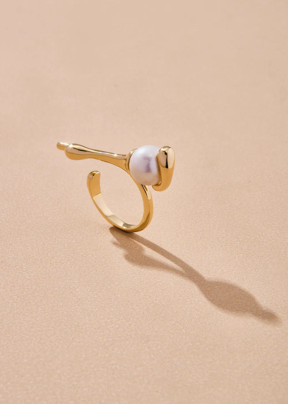 Gold ring with a pearl on a beige background
