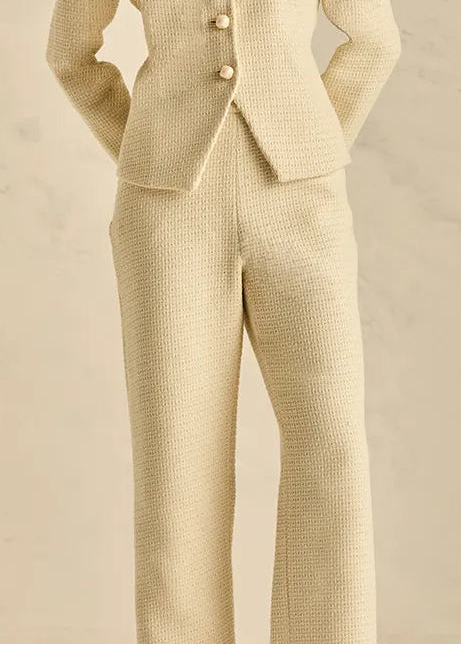 Woman wearing a beige suit against a neutral background
