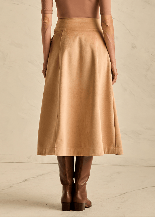 Woman wearing a beige skirt with a plain background