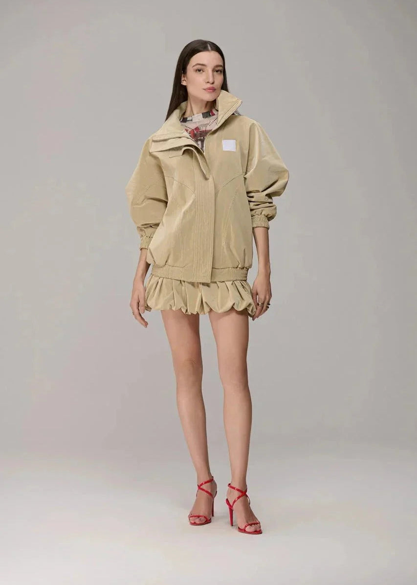 Woman wearing a beige outfit with a matching jacket and skirt on a gray background