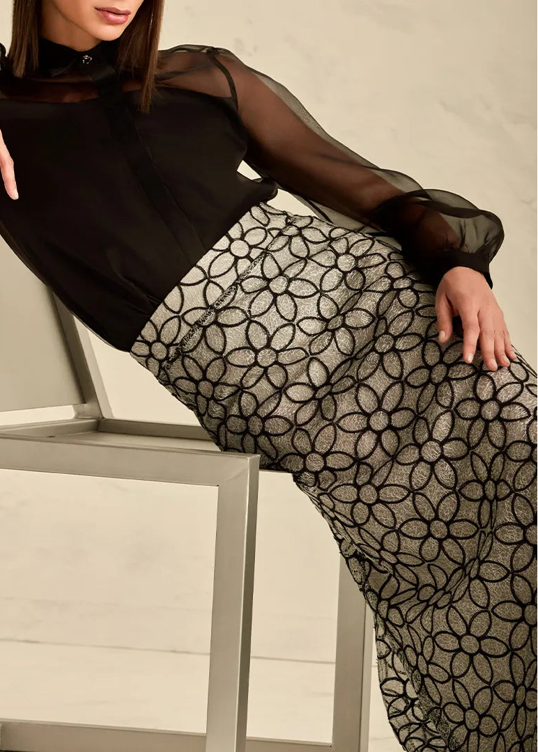 Woman wearing a black top and patterned black and whirw skirt 