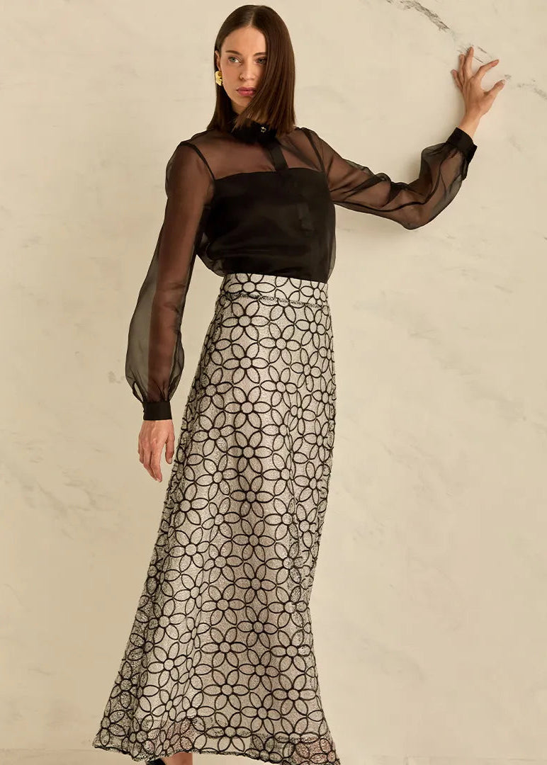 Woman wearing a black sheer top and patterned skirt