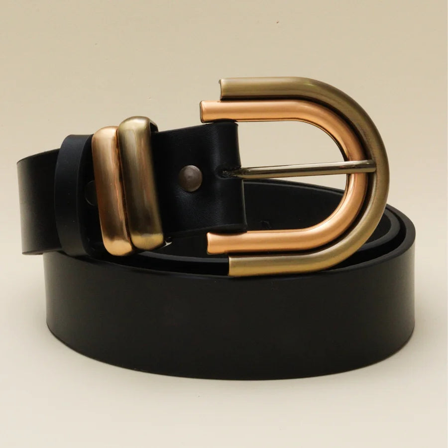 Black leather belt with gold buckle on a beige background