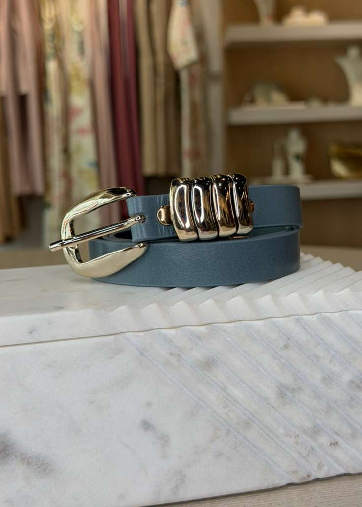 Blue belt with gold buckles on a marble surface