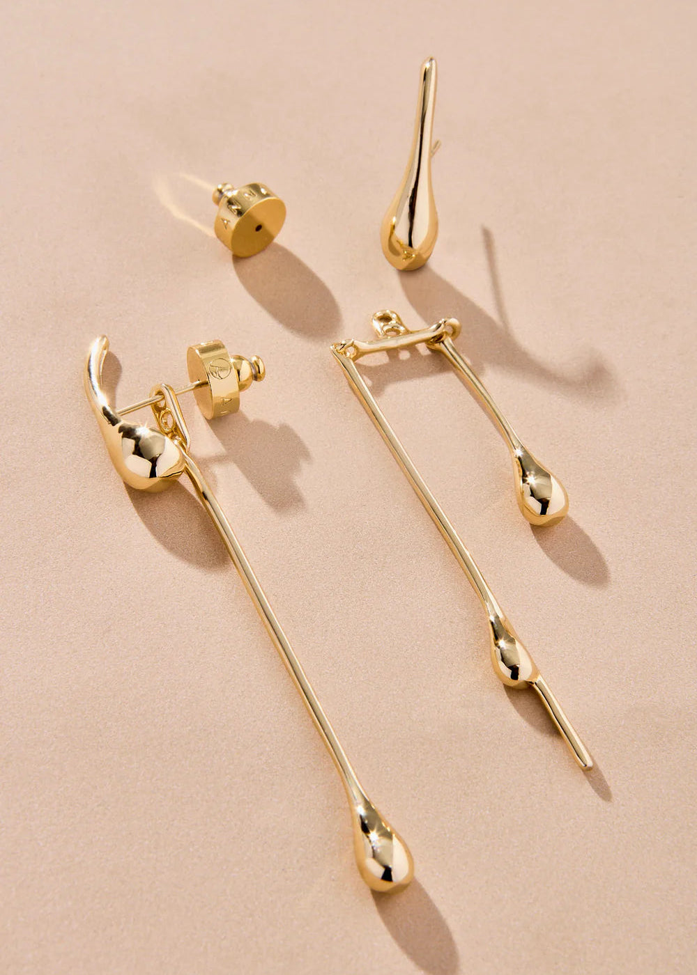 Gold earrings on a beige background
