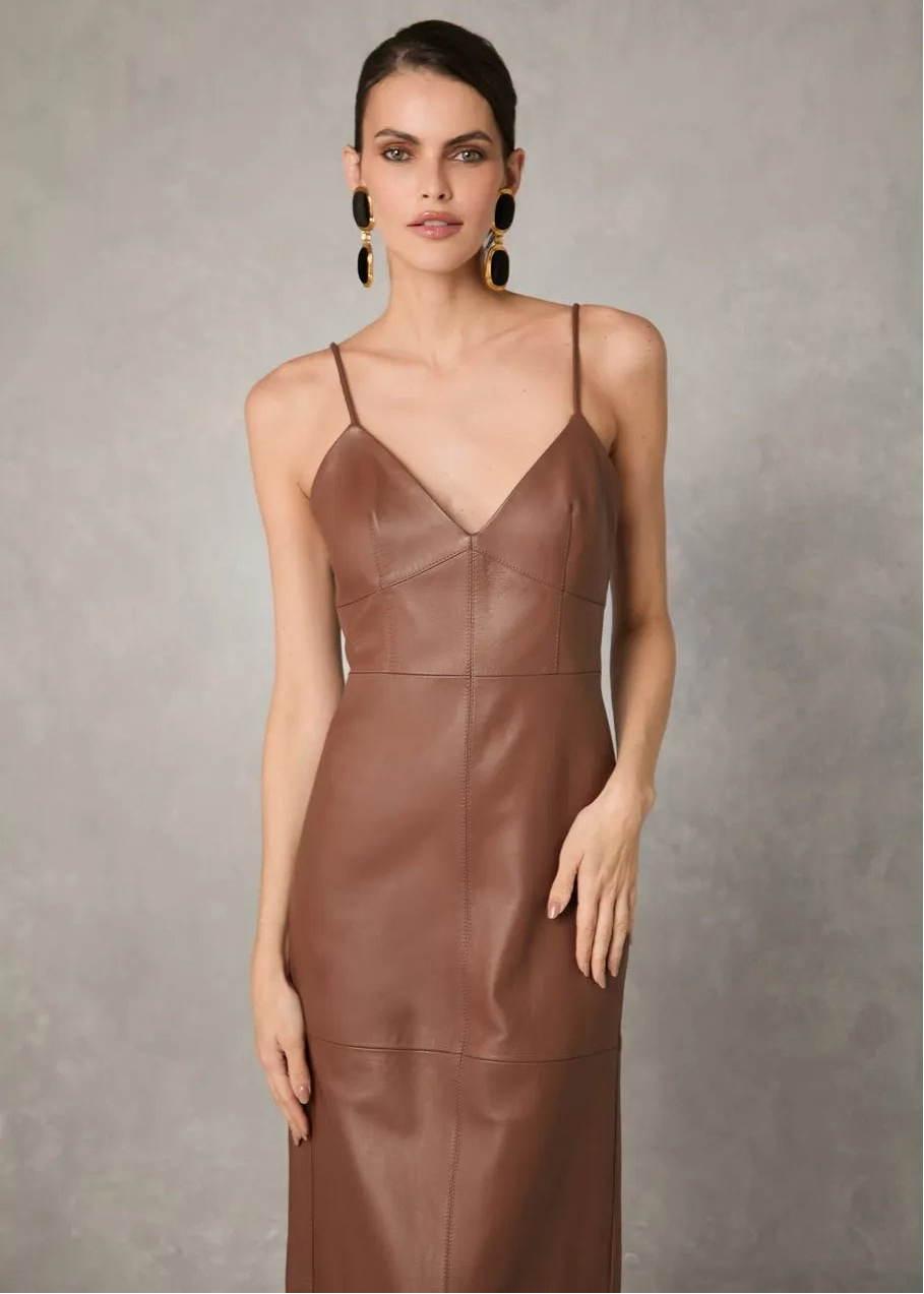 Woman wearing a brown leather dress against a neutral background