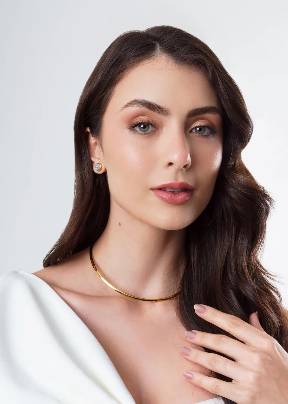 Woman wearing a gold necklace against a white background