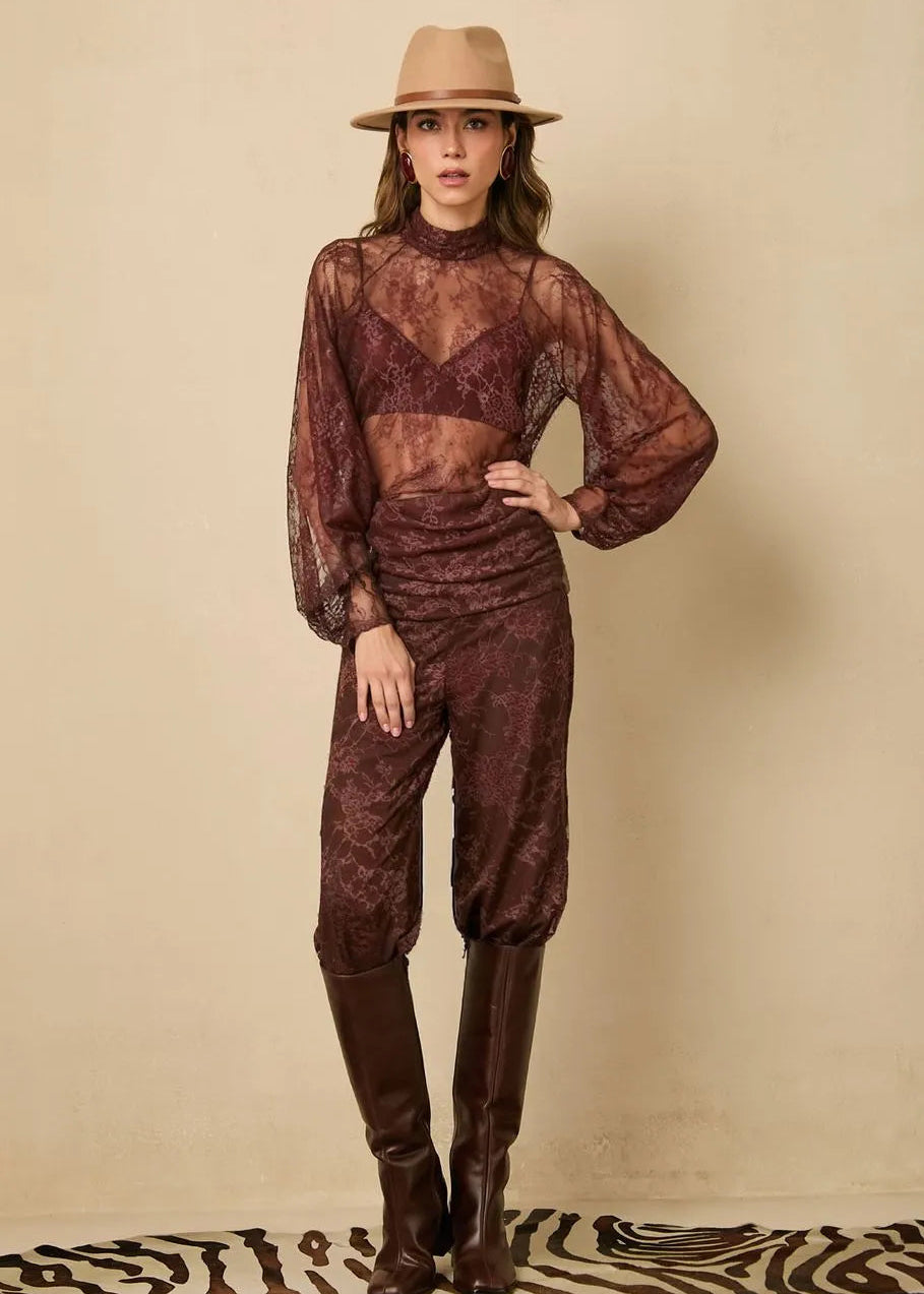Woman wearing a sheer brown outfit with a hat on a beige background