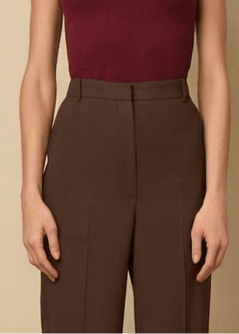 Woman wearing a burgundy sleeveless top and brown pants 