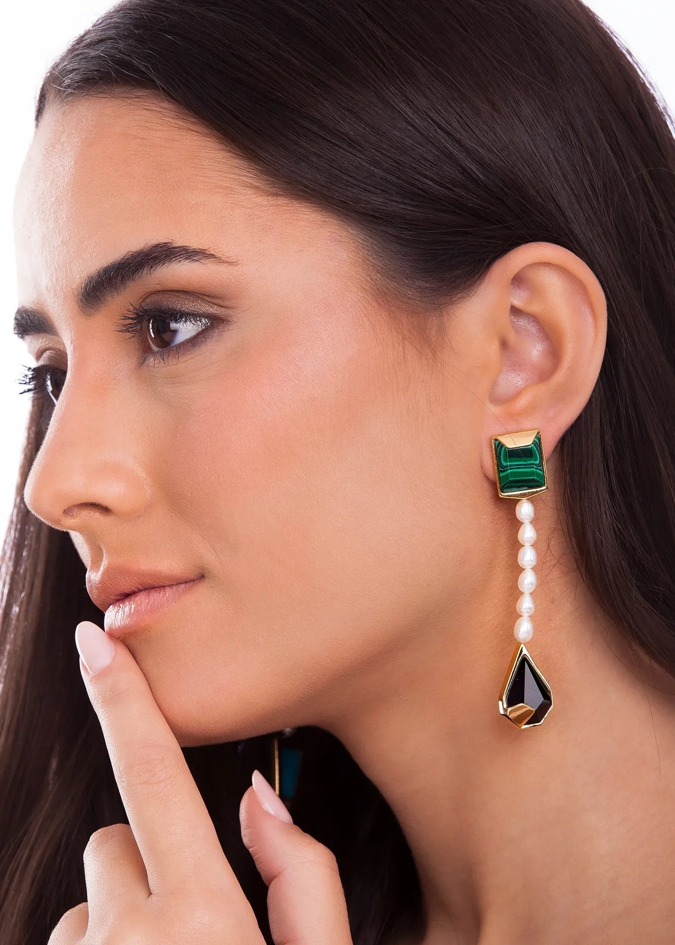 Woman wearing a green and black earring with pearl drop