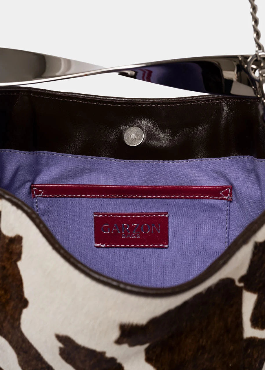 Close-up of a handbag with a cowhide pattern and visible brand logo.