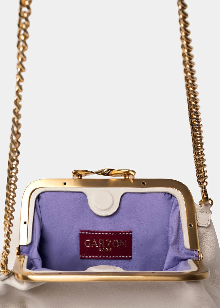  handbag in white leather with a gold-tone frame, lavender purple satin lining, and a burgundy brand patch on the inside.