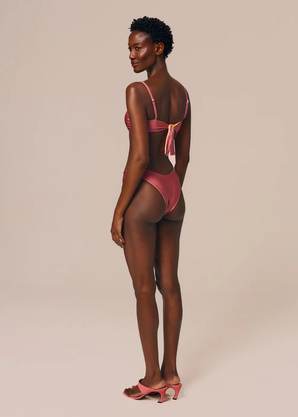Woman wearing a pink bikini against a beige background