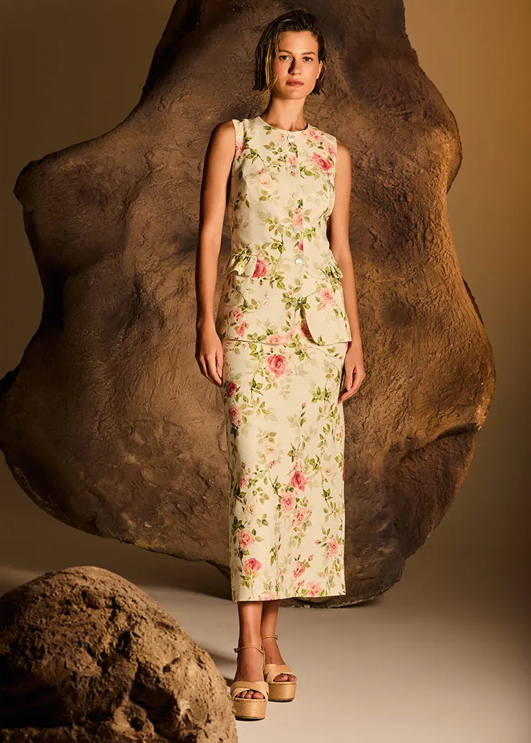 Woman in a floral dress standing next to large rocks with a warm brown background