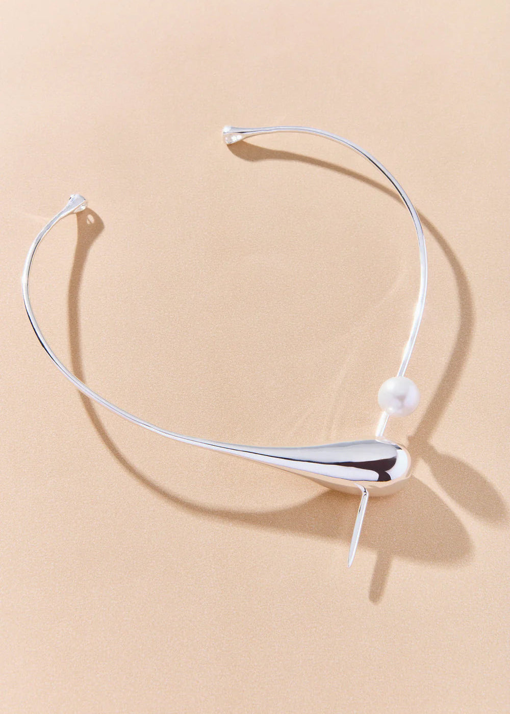 Silver necklace with a pearl on a beige background