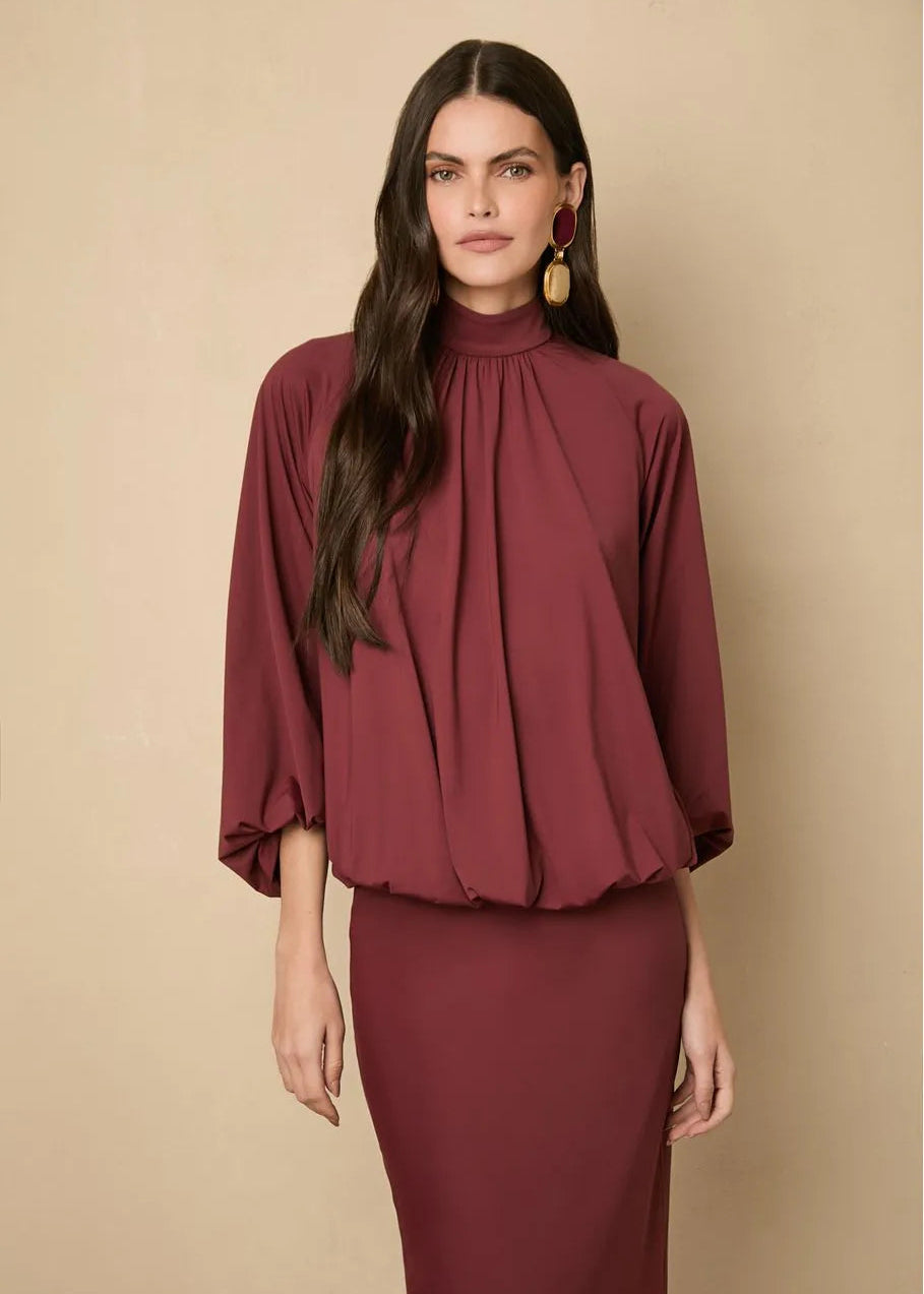 Woman wearing a burgundy dress against a beige background