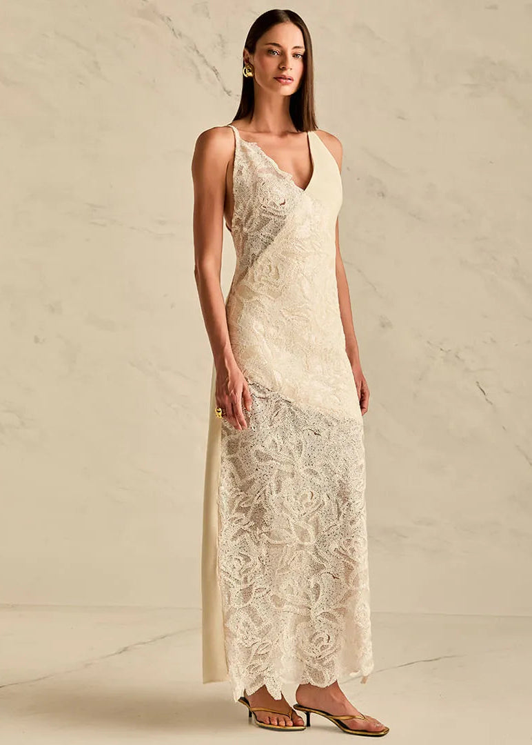Woman wearing a long, elegant dress with lace detailing against a neutral background