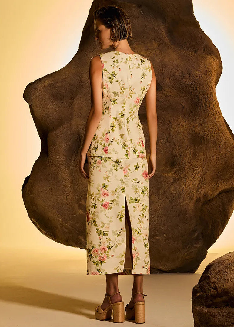 Woman in a floral dress standing against large rocks with a warm glow