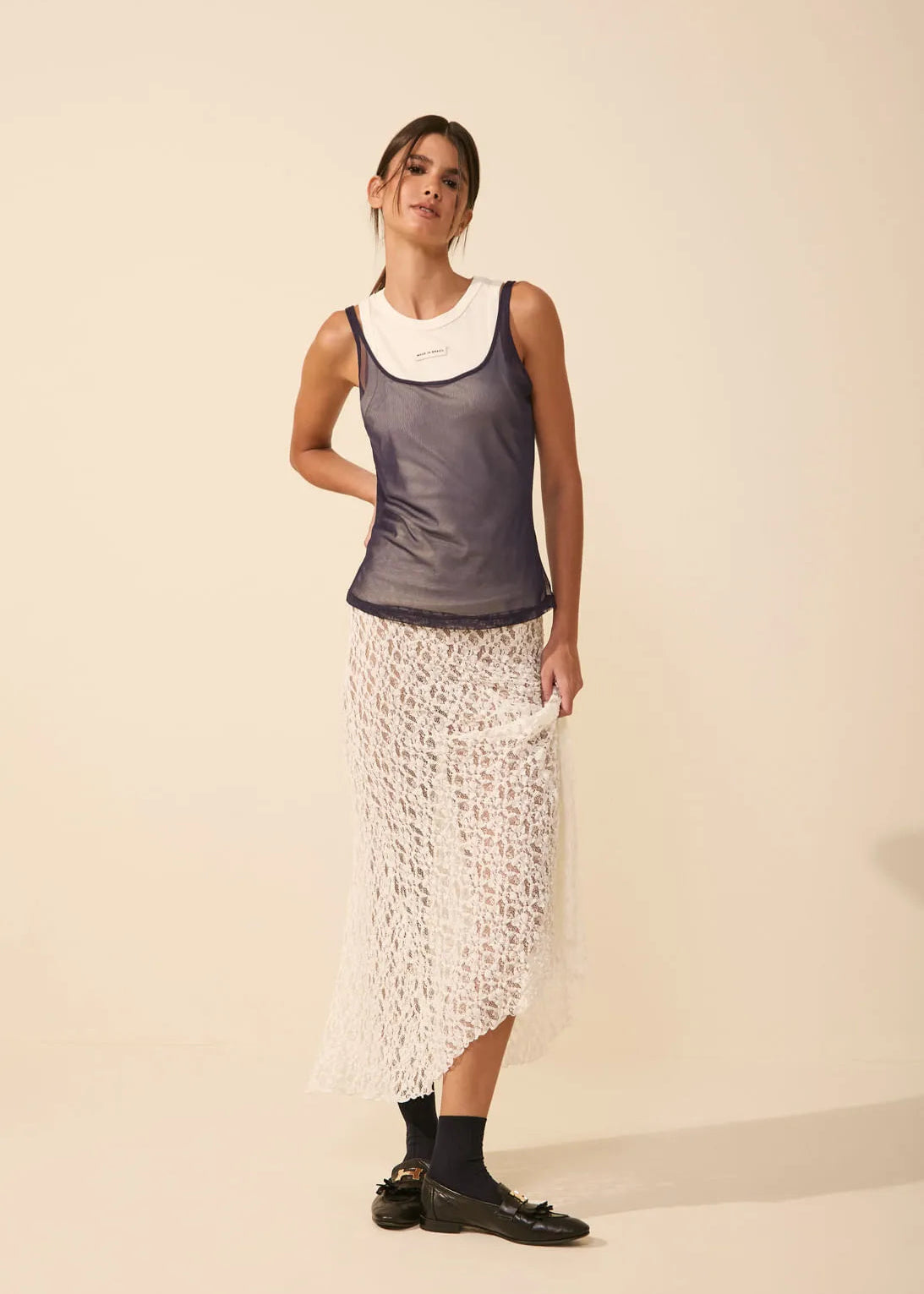 Woman wearing a sleeveless top and patterned skirt on a plain background