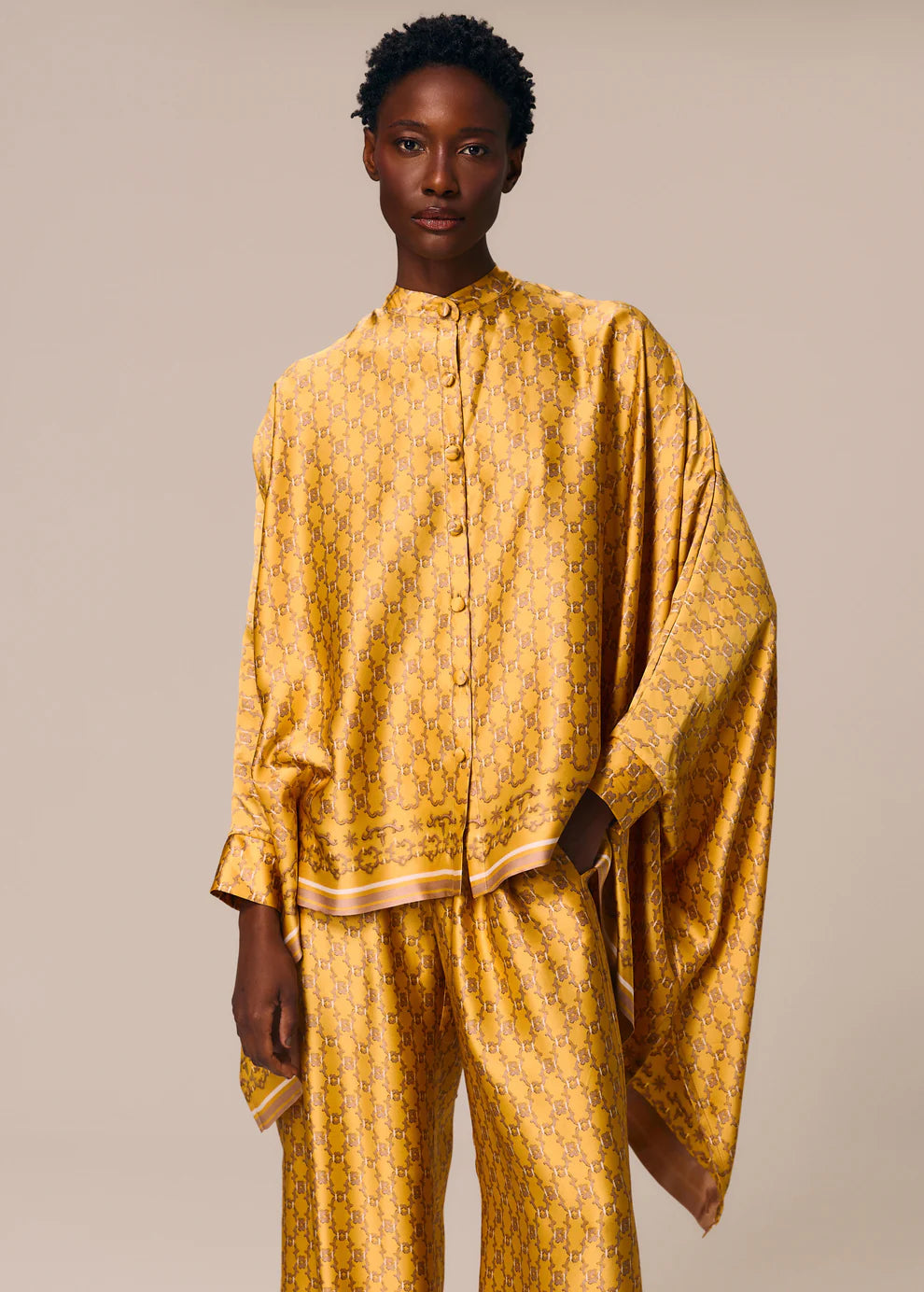 Person wearing a mustard yellow patterned outfit on a beige background