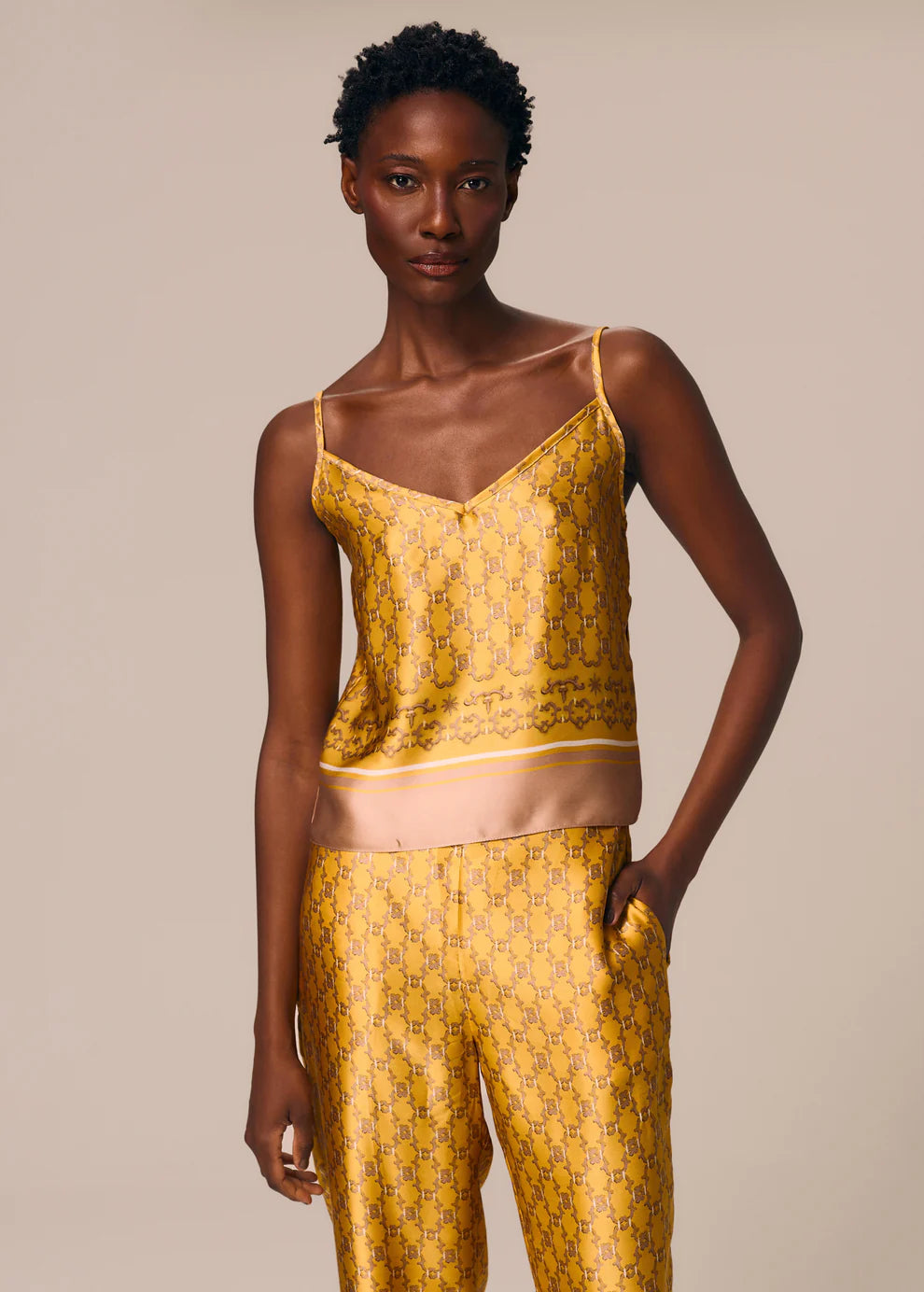 Woman wearing a yellow patterned outfit against a beige background
