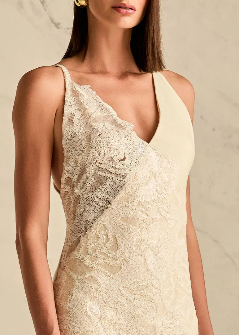 Woman wearing a beige lace dress against a neutral background
