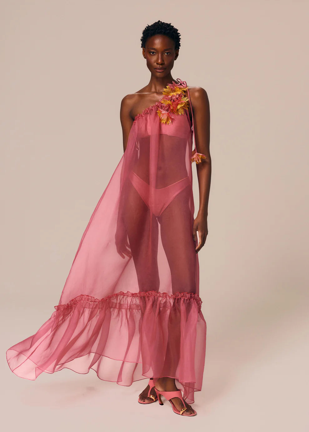 Model wearing a pink sheer outfit with floral details on a beige background