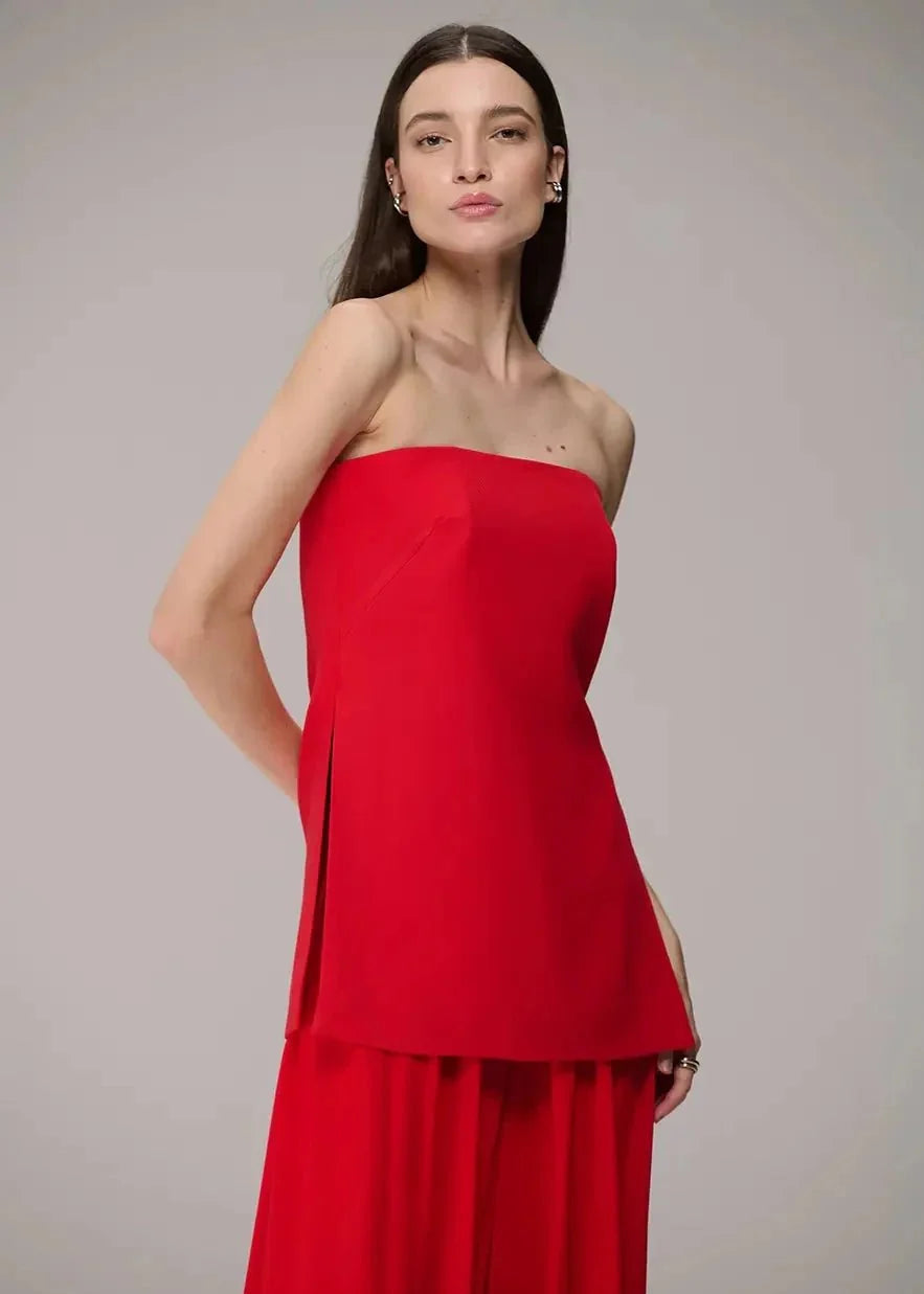 Woman wearing a strapless red outfit against a plain background