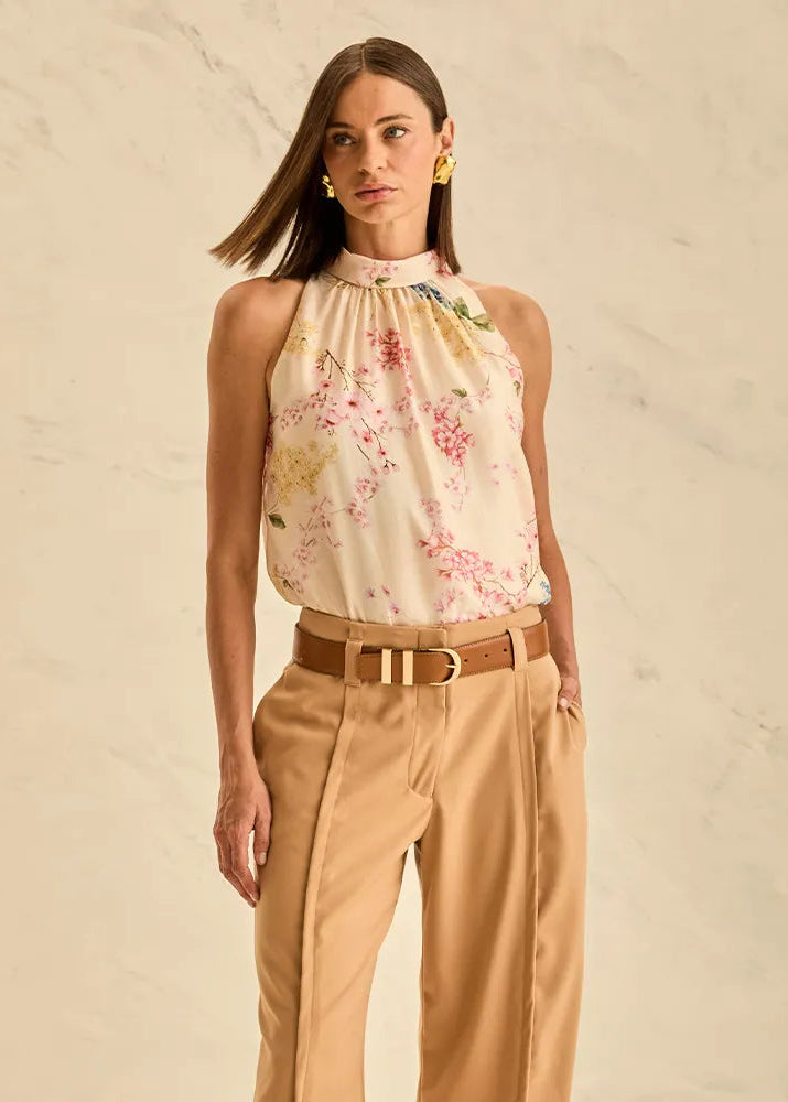Woman wearing a floral top and beige pants against a beige background