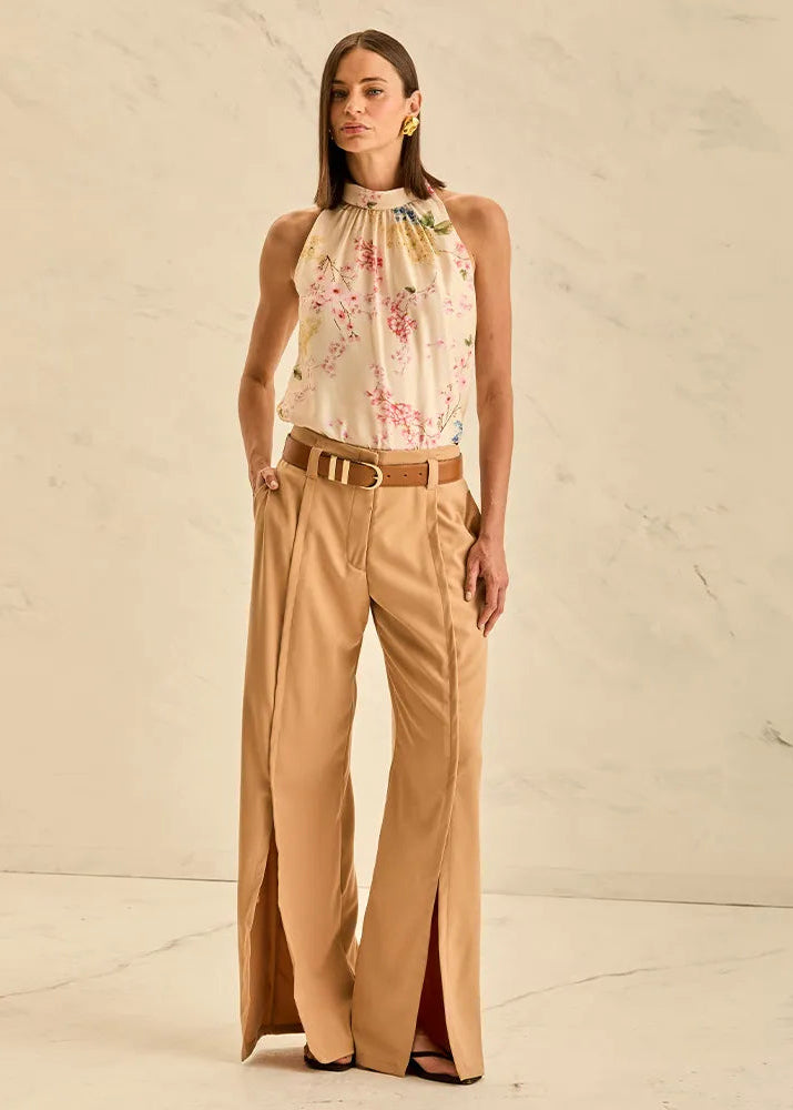 Woman wearing a floral top and beige pants against a neutral background