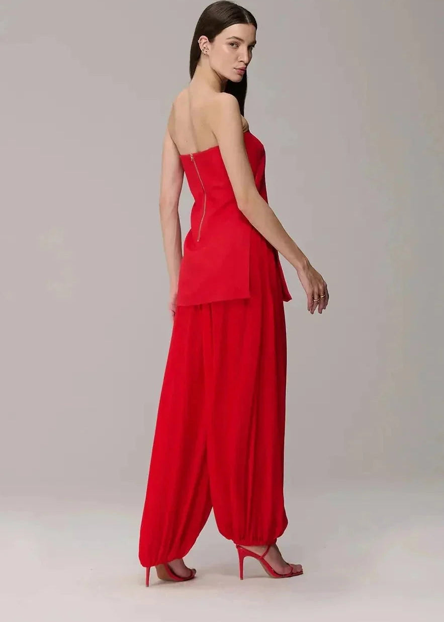 Woman wearing a red strapless blouse and pants on a plain background