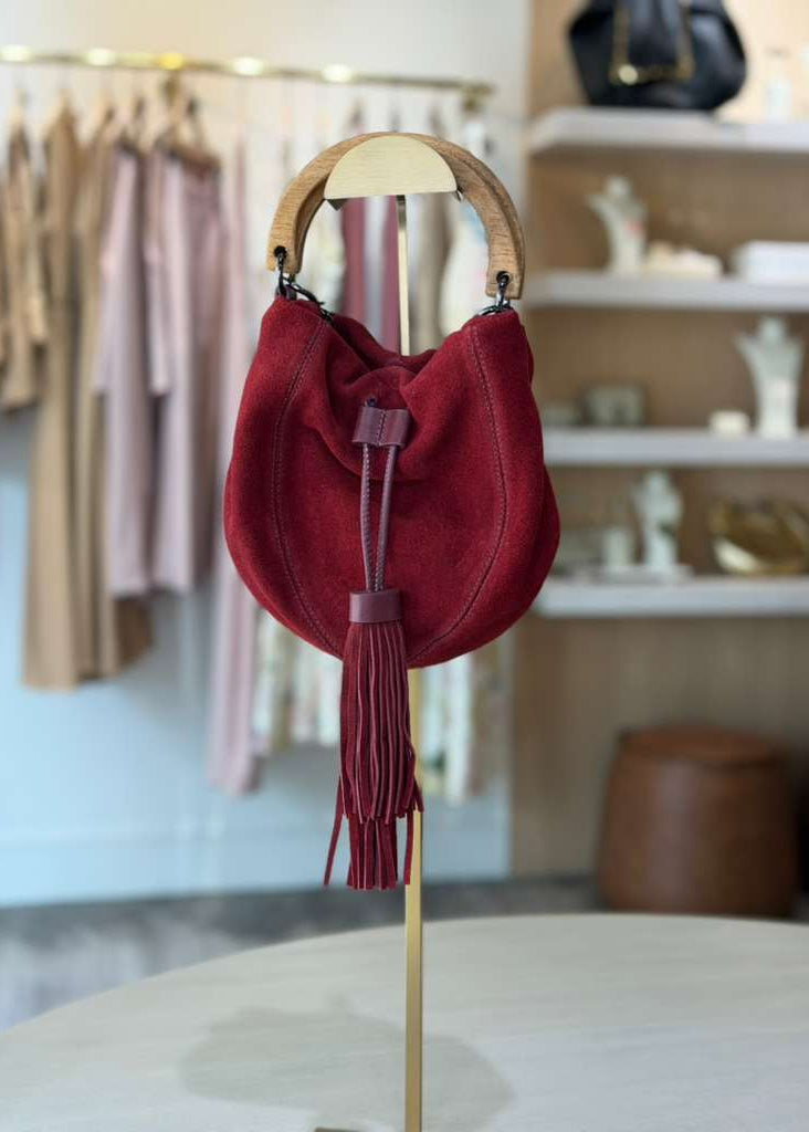 Red handbag with tassel on a mannequin stand in a store setting