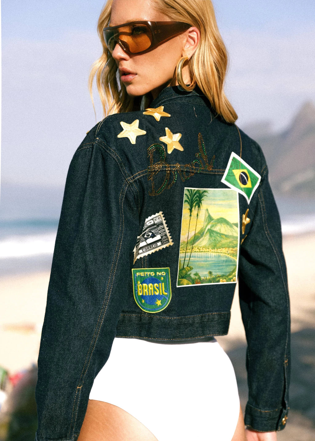 Woman wearing a denim jacket with patches on a beach